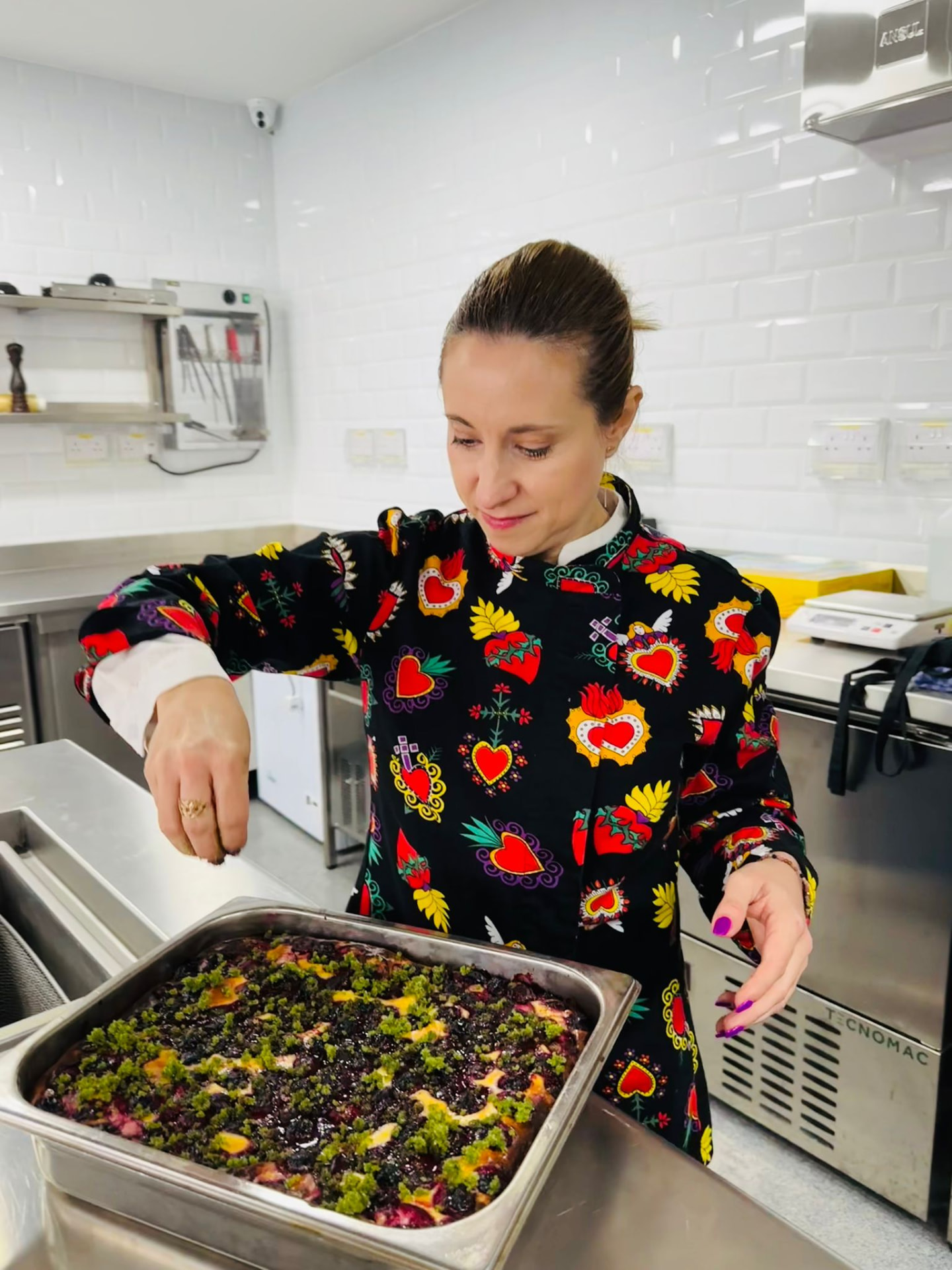 Aminta Georgescu finishing a large tray of fruit focaccia in a professional kitchen